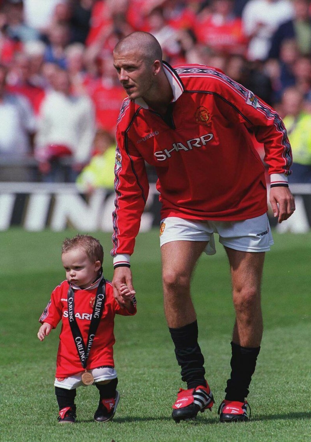 Brooklyn Beckham är bara 1,5 år gammal när den här bilden tas. David Beckham håller lilla Brooklyn Beckham i handen
