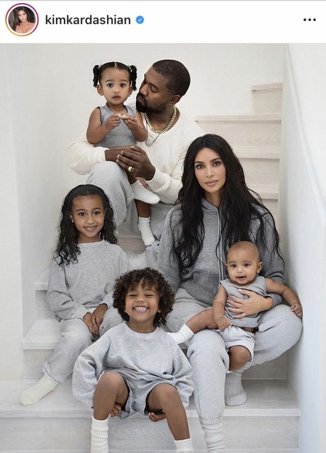 Hela familjen Kardashian-West i mjukiskläder. Kim Kardashian, Kanye West och deras barn sitter i en trapp iklädda grå mjukisar