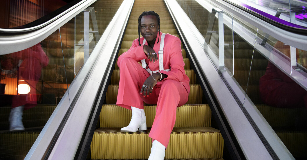 Tusse Chizas plan är att vinna Eurovision song contest i Rotterdam. Tusse Chiza i en rosa kostym och vita klackar. Ler mot kameran.
