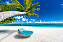 Vit strand och blått hav med en solstolsgunga
