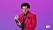 The Weeknd håller i ett pris och har röd kavaj på sig