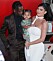 Kylie Jenner står i vit klänning och håller dottern Stormi och Travis Scott är på väg att pussa Stormi på kinden